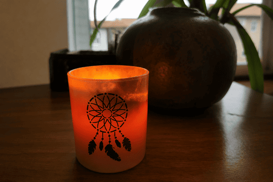 Une expérience pensée pour votre confort Bougie dans un verre avec une plante en arrière-plan, illustrant une ambiance de détente et de confort pour un massage bien-être à domicile